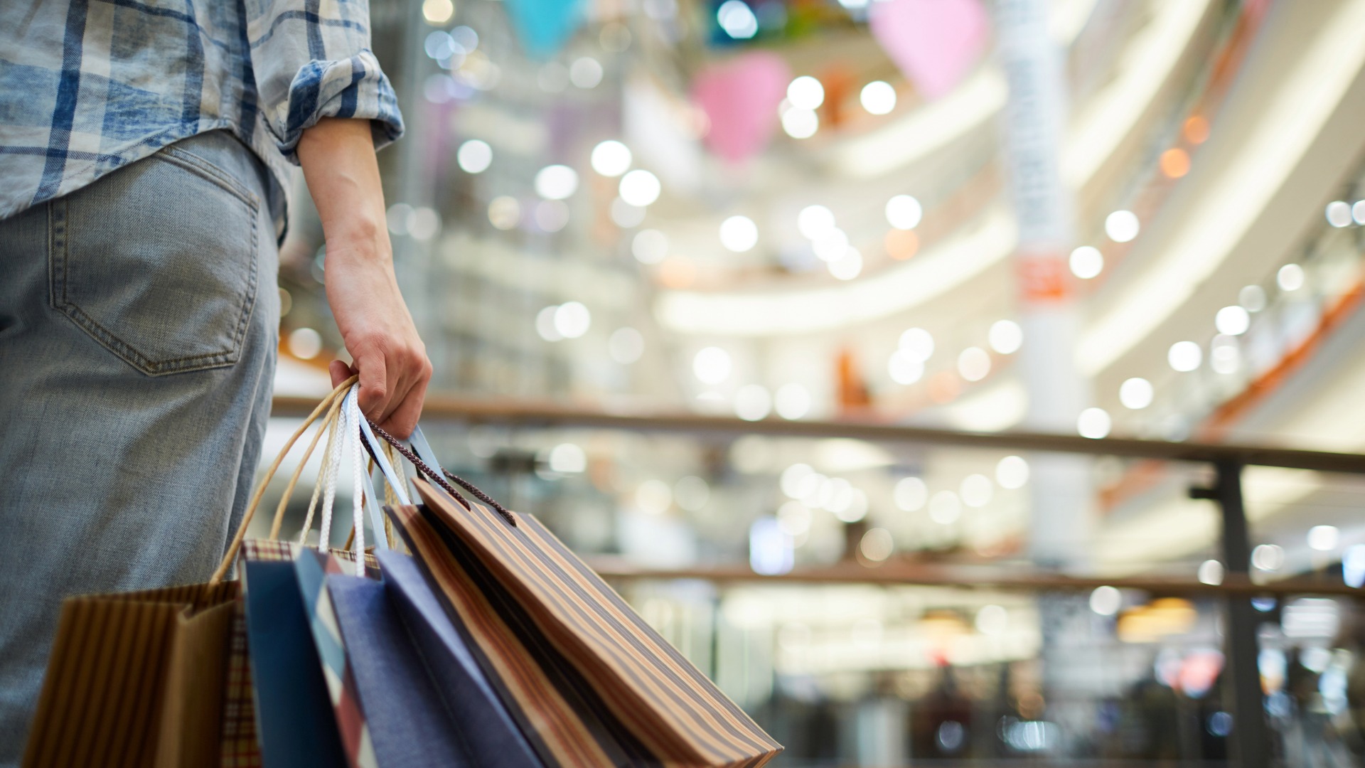A person holds bags full of items they purchased at a shopping center. 